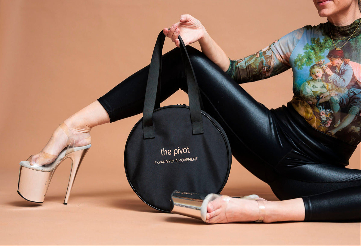Person holding a black bag labeled 'the pivot' on a beige background